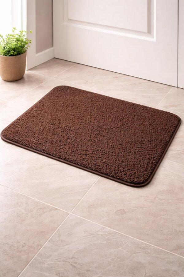 Brown anti-skid bath mat placed on a tiled bathroom floor near a door with a soft textured surface